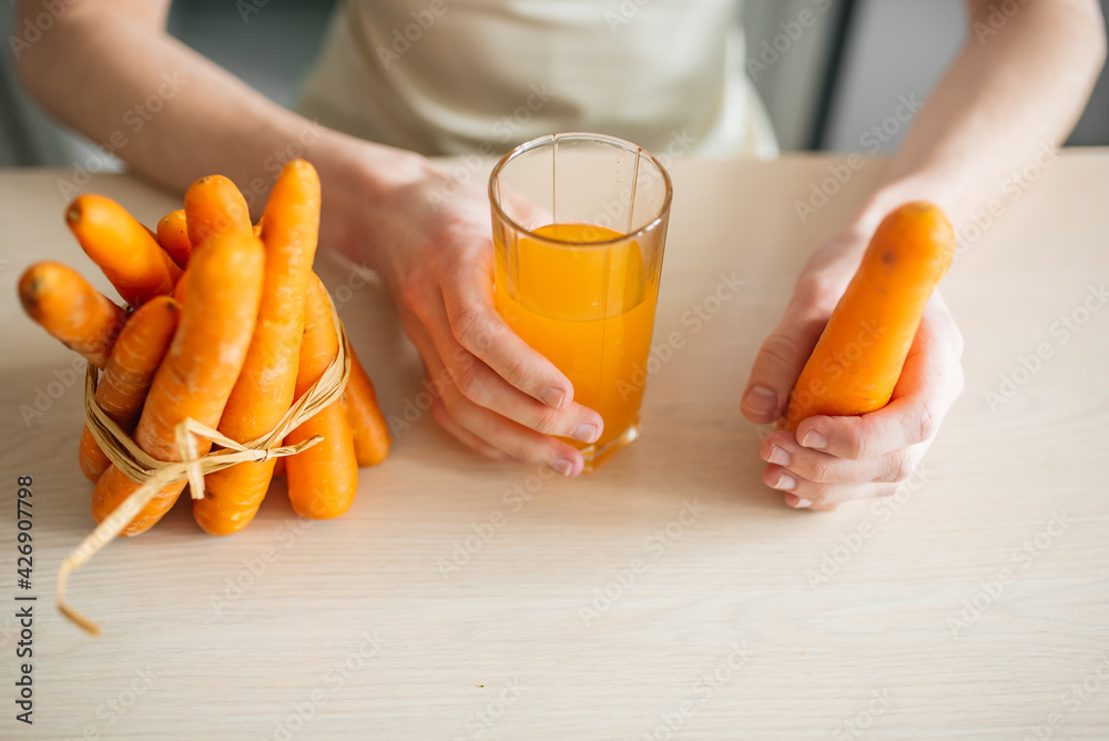 carrots and carrot juice in a glass beaker in the kitchen. Young guy and healthy food carrots and carrot juice in a glass beaker in the kitchen. Young guy and healthy food
