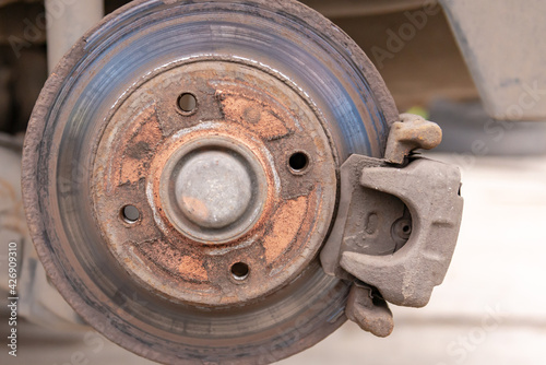 Heavily worn brake disc. Car brake disc after removing the wheel. A rusty disk that needs to be replaced.