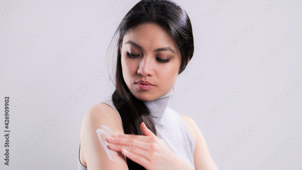 Young woman applies moisturizer to her arm - studio photography Young woman applies moisturizer to her arm - studio photography