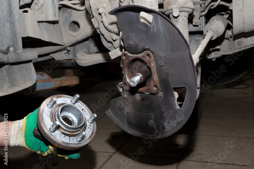  Auto mechanic hands holding the wheel hub. Close-up. Replacement of spare parts in a car service.