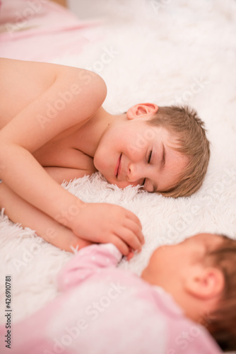 brother looks at his newborn sister and smiles at her 