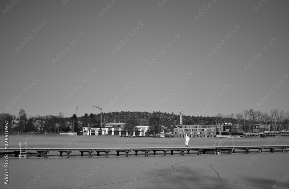 Naklejka premium Lake Ukiel in Olsztyn in the winter time and a man dressed in white walking on the bridge