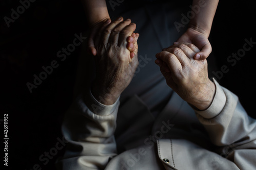 very elderly great-grandmother and granddaughter hold hands