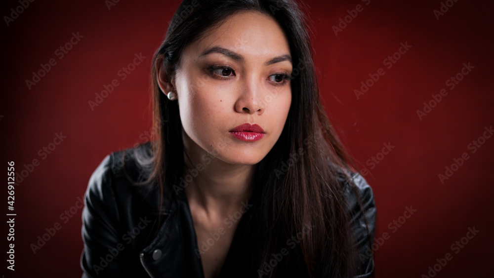 Young thoughtful woman against a red background - studio photography