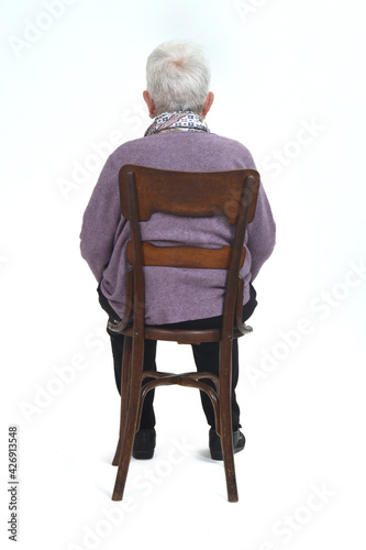 rear view of a senir woman sitting on chair on white background photo