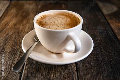 A cup of coffee on a saucer, on a wooden background.