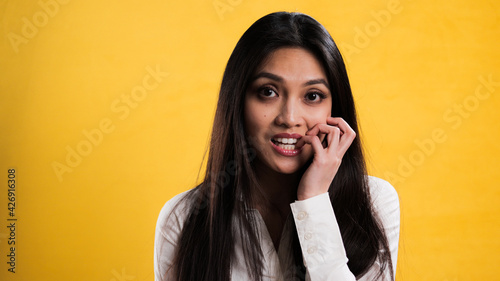 Young excited woman chews on her fingernails - studio photography