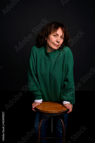 Adult brunette woman in a green sweater in the studio. Beautiful Model Age. Modern fashion for appearance. Copy space