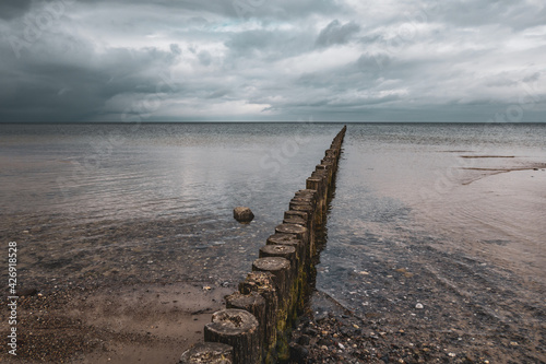 groynes on the beach of the Baltic Sea and the sky is dramatically cloudy