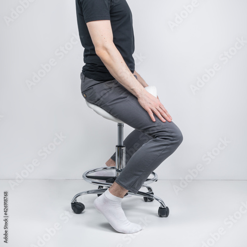 Man sitting on ergonomic saddle chair. The right orthopedic chair for a healthy back and correct posture.