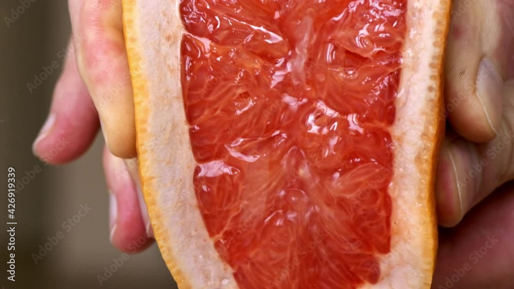 A woman squeezes juice from a grapefruit. Slow motion