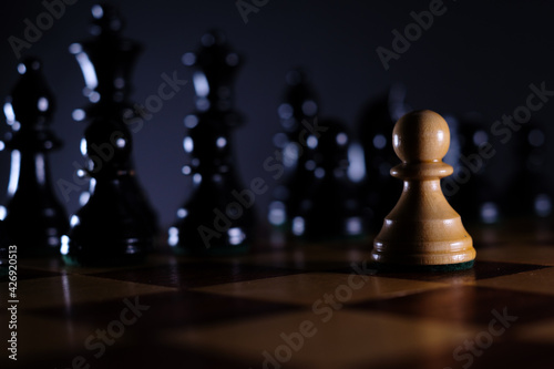 a white pawn is alone in front of the black pieces on the chessboard