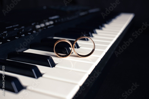 Two wedding rings on a piano with dark background