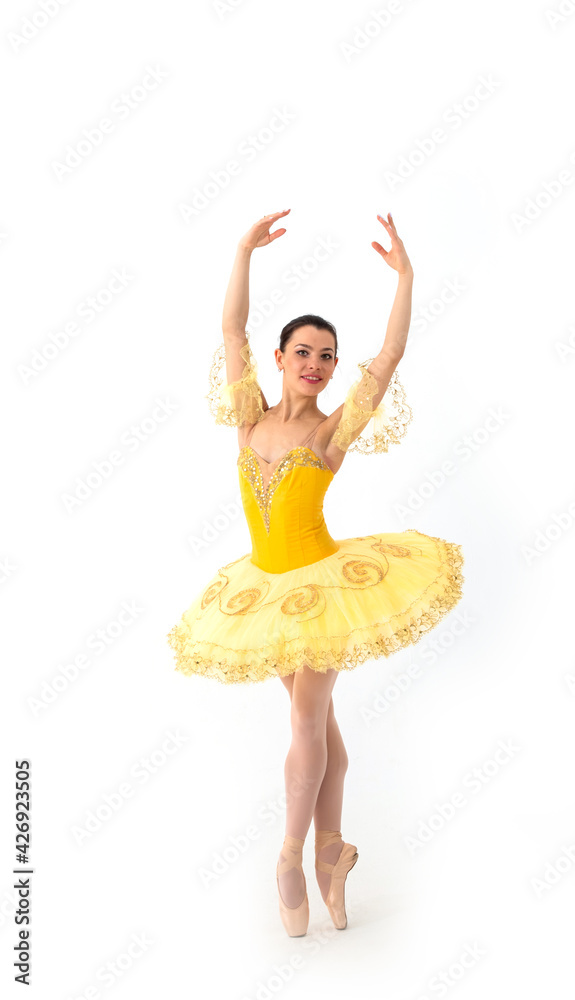 Naklejka premium Young modern ballerina with yellow tutu doing the pose on white background.