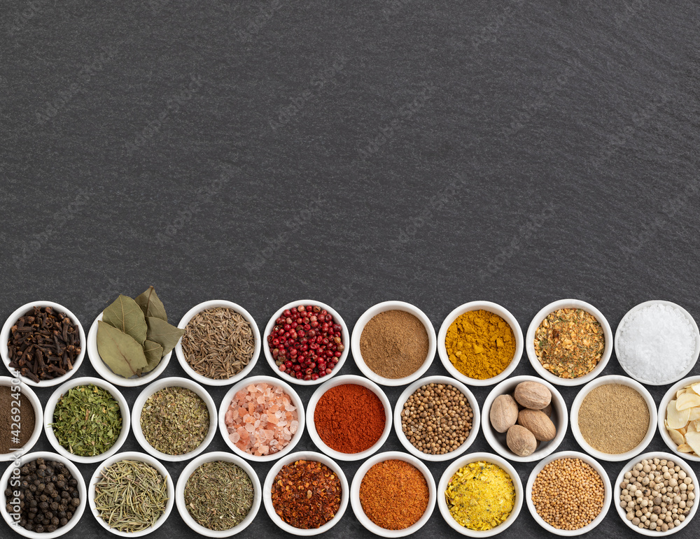 Assorted seasonings and herbs over stone background with copy space Assorted seasonings and herbs over stone background with copy space