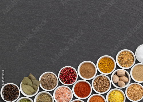 Assorted seasonings and herbs over stone background with copy space