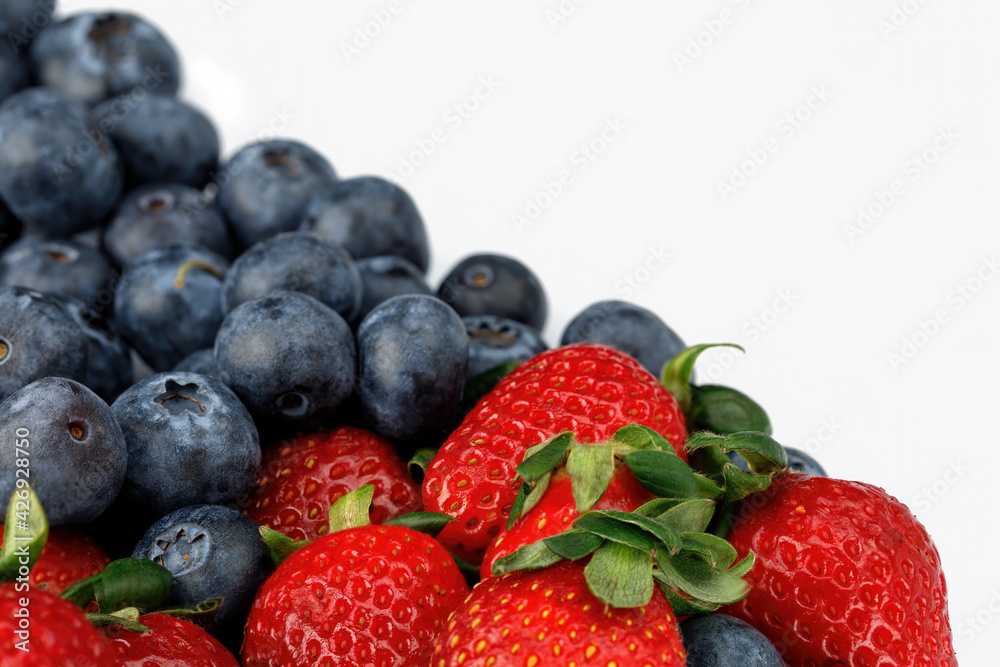Strawberries and blueberries isolated on a white background. Diagonal line from left to right Strawberries and blueberries isolated on a white background. Diagonal line from left to right