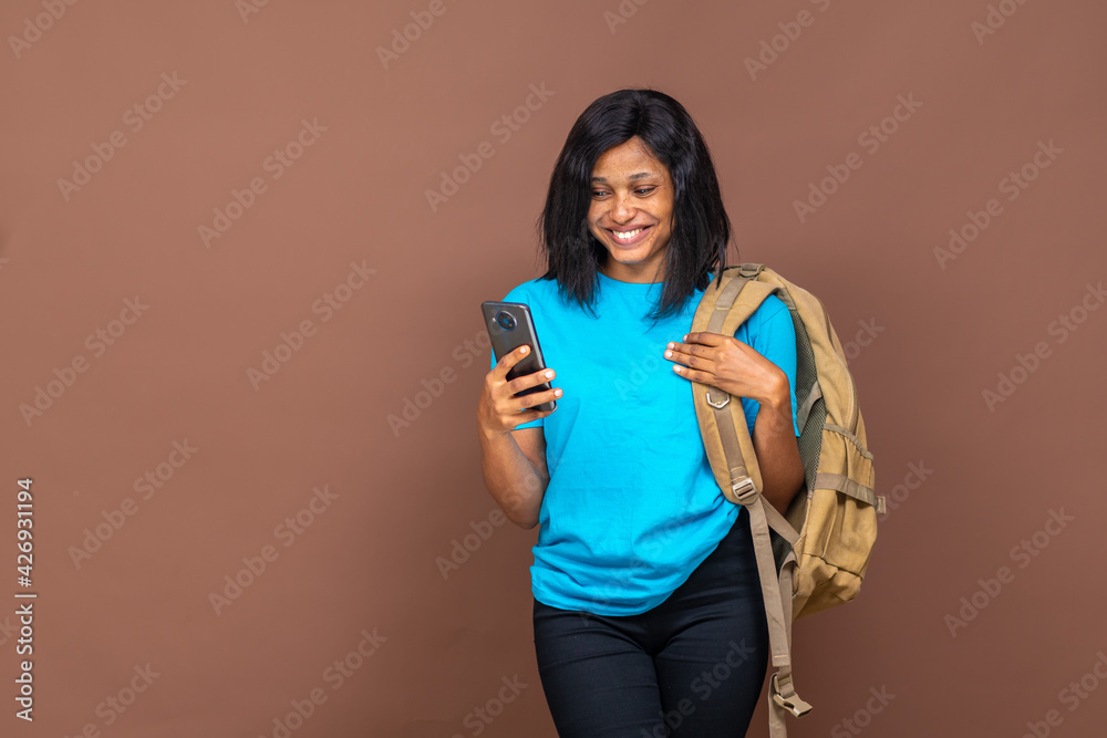 black female student smiling while using her phone, on a plain background with copy space black female student smiling while using her phone, on a plain background with copy space
