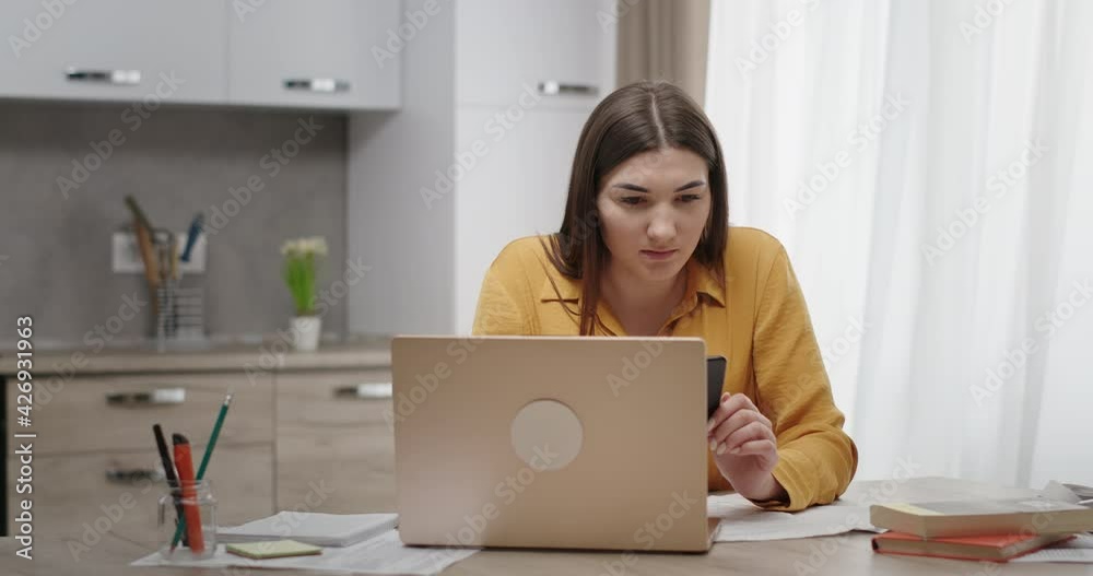 Young woman working at home on a laptop receives a happy sms good news rejoices can't believe her eyes screams with happiness Young woman working at home on a laptop receives a happy sms good news rejoices can't believe her eyes screams with happiness