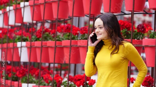 Young woman talking on the phone in a square full of flowers and colors