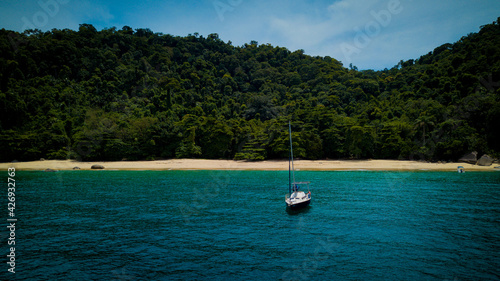 A sailboat navigates in the limpid waters of the Angra dos Reis bay, Rio de Janeiro - Brazil