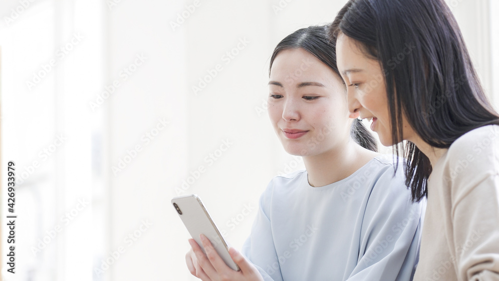 一緒にスマホを見る二人の女性 一緒にスマホを見る二人の女性