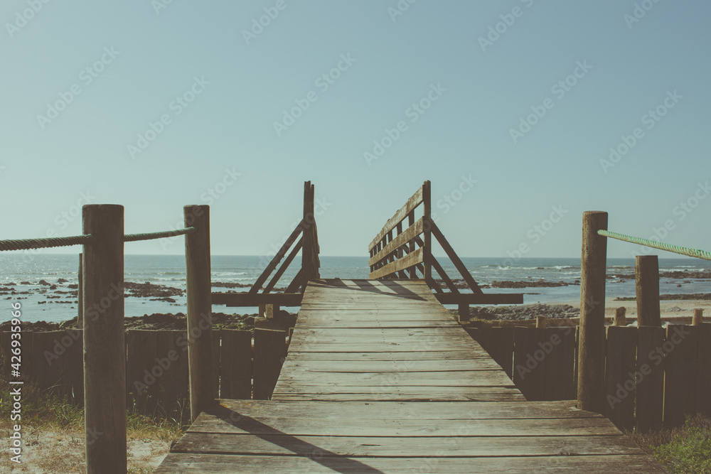 Fototapeta premium Wooden bridge to the beach at the Northern Litoral Natural Park in Esposende, Portugal. Scenic colorful sunset at the sea coast.