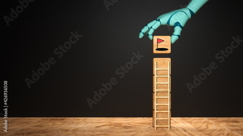 robot hand adding a cube with a target symbol to a stack of cubes on wooden base in front of a blackboard