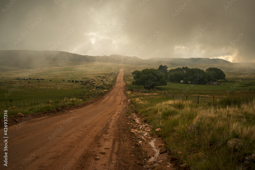 dirt road that goes away towards the cloudy mountains