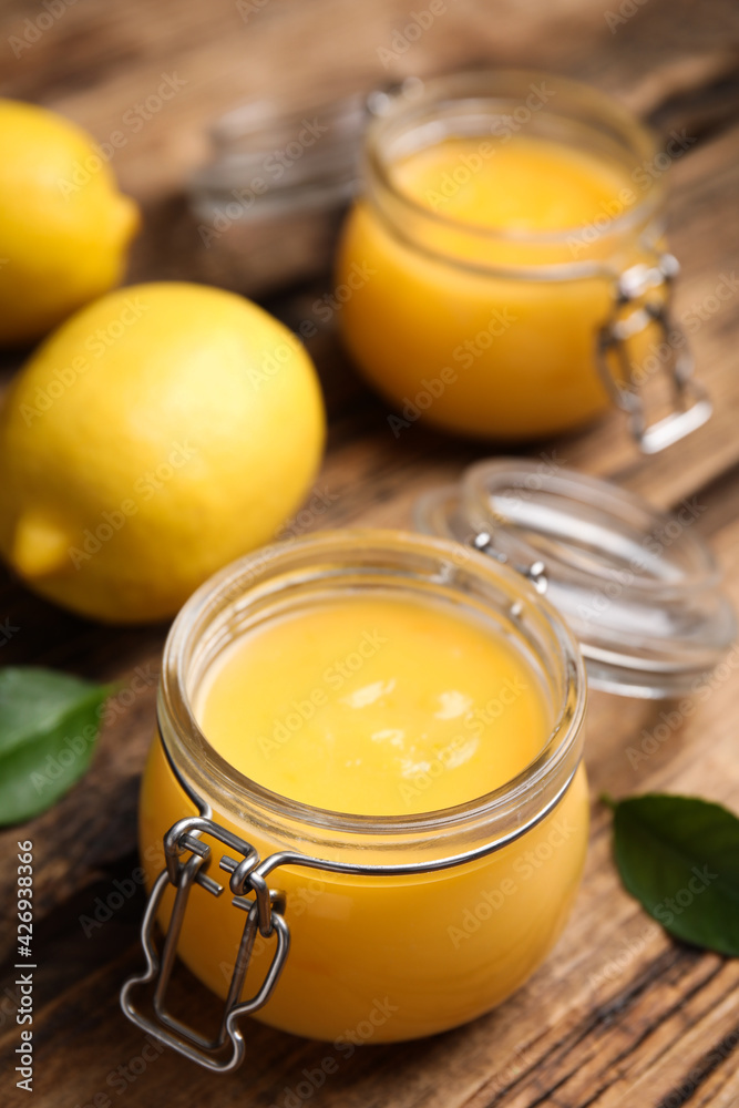 Delicious lemon curd in glass jar on wooden table Delicious lemon curd in glass jar on wooden table