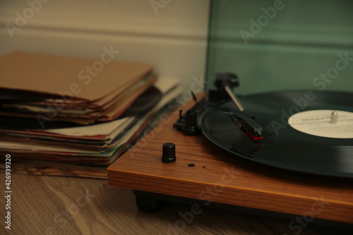 Stylish turntable and vinyl records on floor indoors, closeup