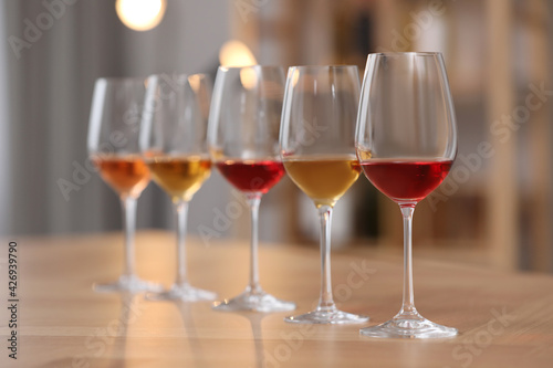 Different sorts of wine in glasses prepared for tasting on wooden table indoors