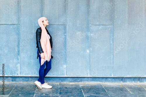 Принти на полотні Woman in profile leaning against a wall with space for copy looking up pink partner on the head in symbol fighting cancer