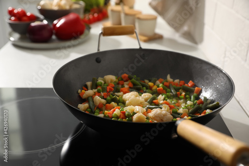 Frying pan with mix of fresh vegetables in kitchen