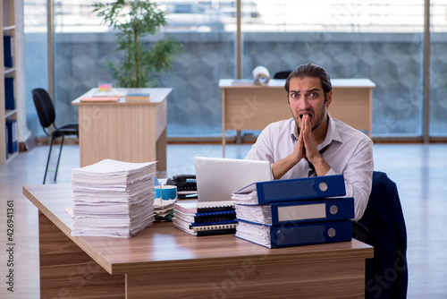 Young male employee unhappy with excessive work in the office