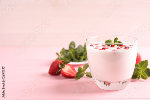 Delicious drink with strawberries on pink table, space for text