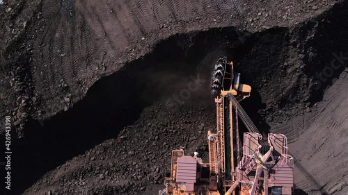 View from above. Coal mining. A large bucket wheel excavator shovels coal from a pile.