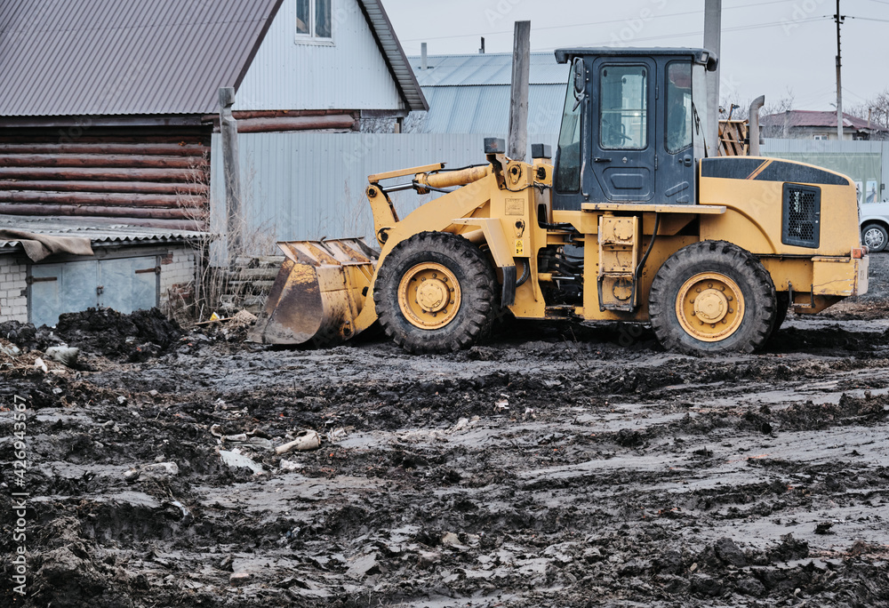 Excavator tractor with bucket working in mud, preparation for construction