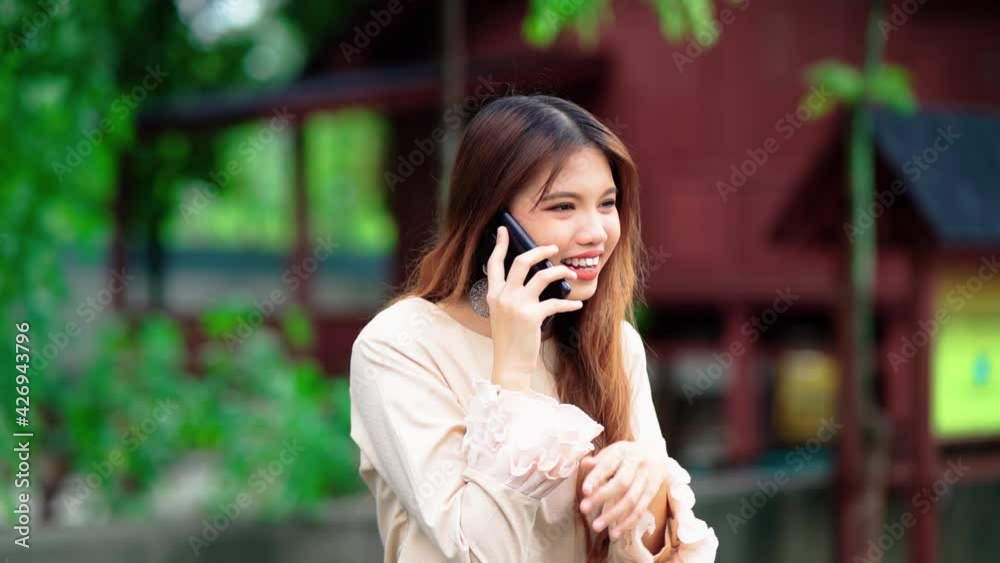 beautiful malay girl using smart phone with malay house in the background beautiful malay girl using smart phone with malay house in the background