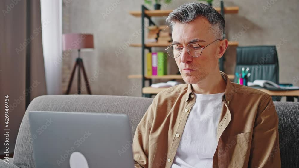 Close up of middle aged man freelancer working on laptop, typing article or report on computer and reading it Close up of middle aged man freelancer working on laptop, typing article or report on computer and reading it