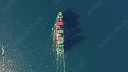 Ultra large container ship sailing at sea, aerial top down view. Cargo ship loaded with various colourful containers, drone shooting. High quality 4k footage