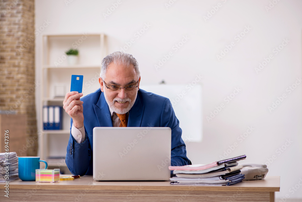 Old businessman employee holding credit card in the office Old businessman employee holding credit card in the office