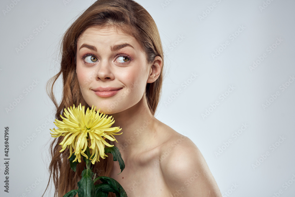 Portrait of a beautiful woman with a yellow flower on a light background cropped with Copy Space Model