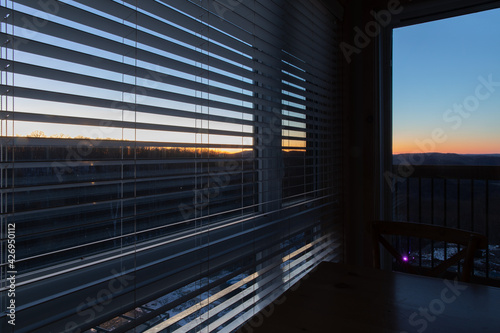 Vue d'une fenêtre à l'intérieur d'une pièce sombre avec coucher de soleil derrière une colline photo