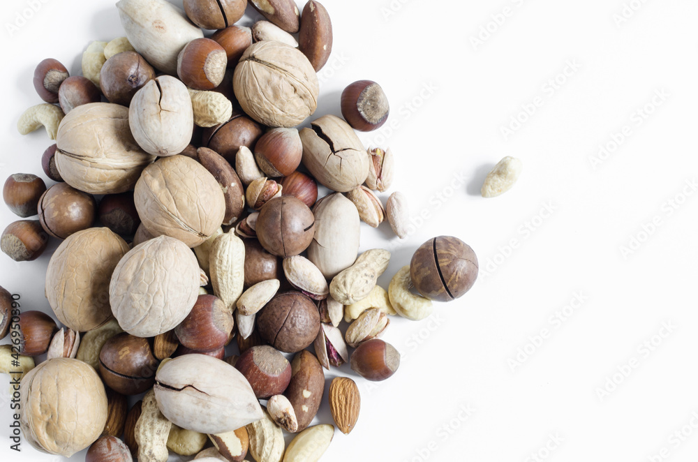 a scattering of different nuts on a white background assorted nuts hazelnuts almonds pecans peanuts macadamia walnuts top view kopi space