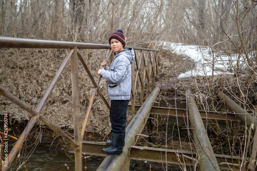 a boy stands on a dismantled bridge on a spring day