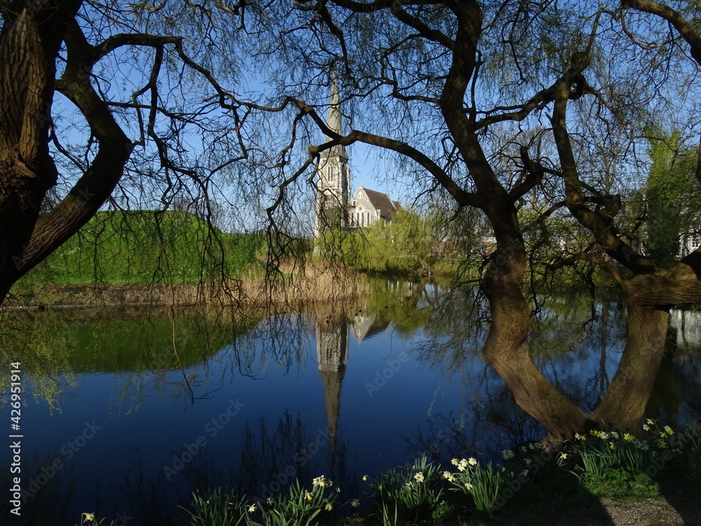 reflection of trees in water with church in the background reflection of trees in water with church in the background