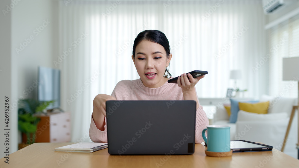 Young happy attractive beautiful asia female staff laugh talk on mobile phone relax comfort sit work on desk table at home. Remotely work on distance job telesale or secretary career for business. Young happy attractive beautiful asia female staff laugh talk on mobile phone relax comfort sit work on desk table at home. Remotely work on distance job telesale or secretary career for business.