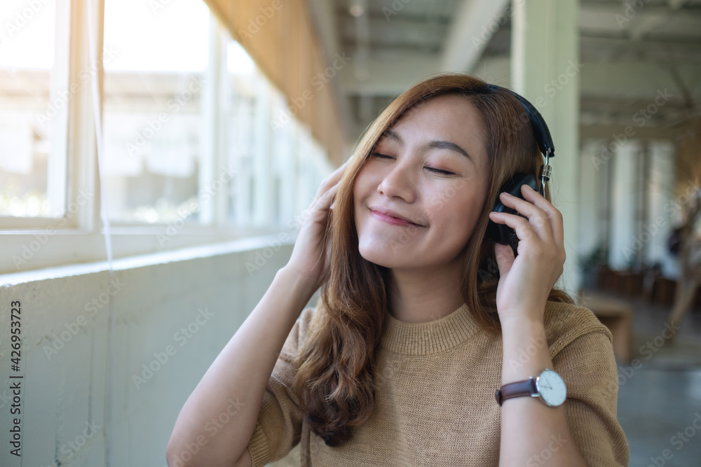 Portrait image of a beautiful young asian woman enjoy listening to music with headphone Portrait image of a beautiful young asian woman enjoy listening to music with headphone