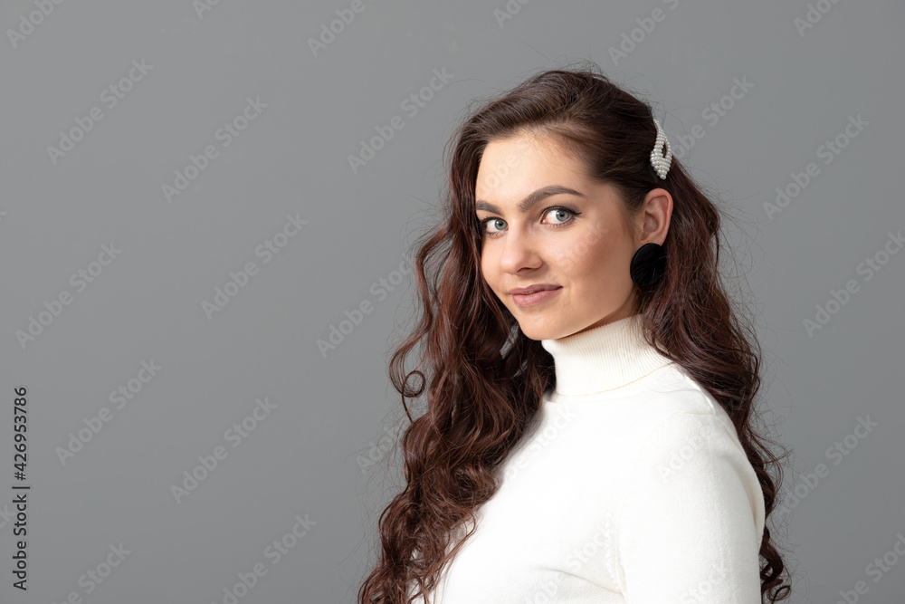 portrait of beautiful sensual woman with long curly hair against gray background